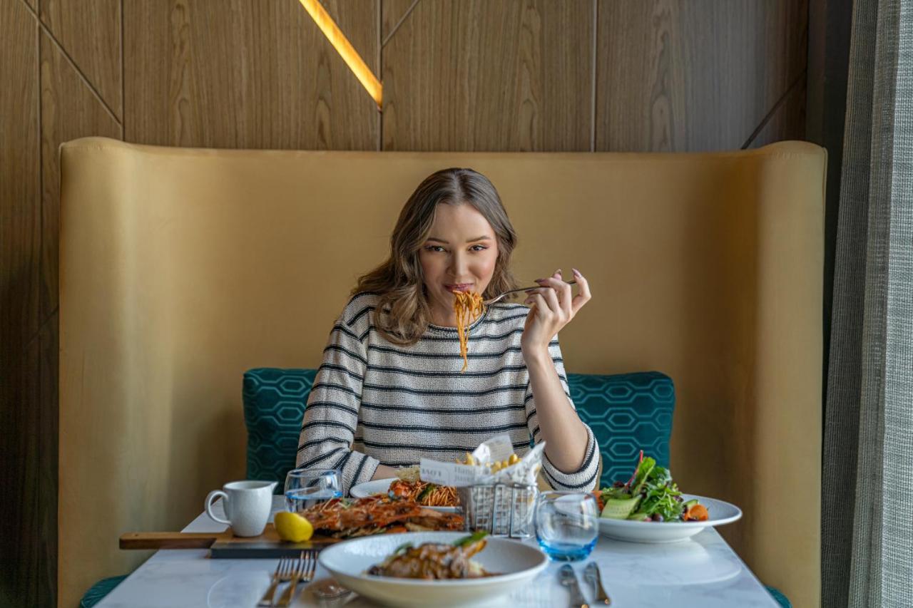 Pullman Sharjah Hotell Exteriör bild A woman eating at a restaurant
